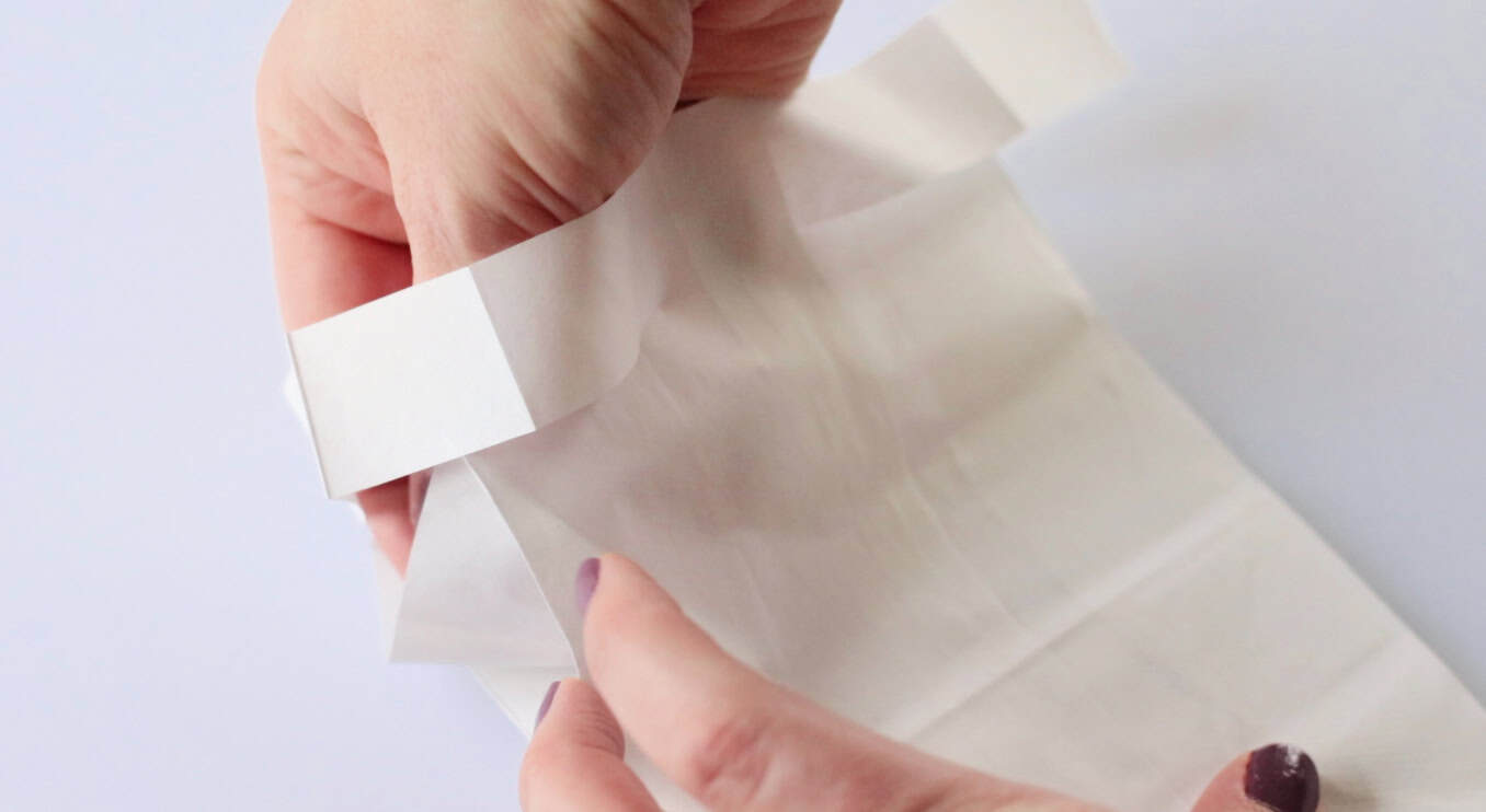 Fingers folding bag sides to form sleeves.