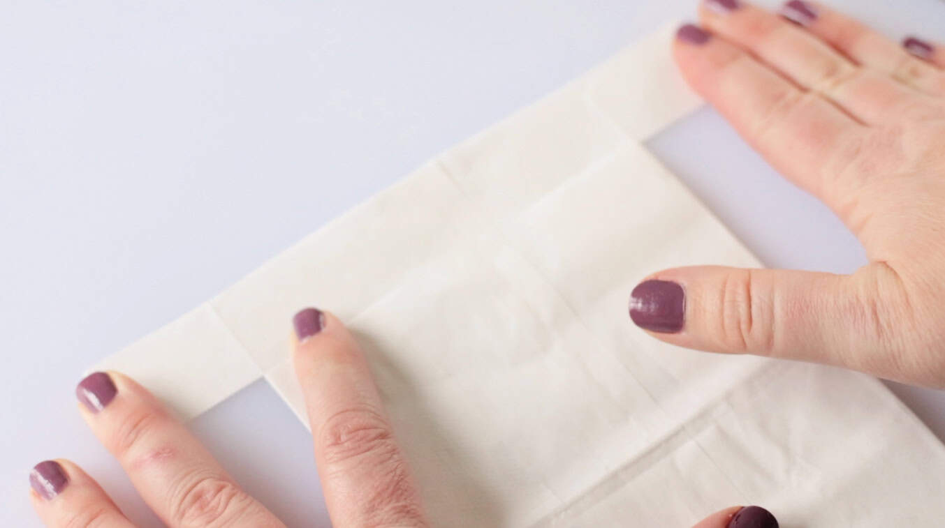 Hands pressing white paper bag open.