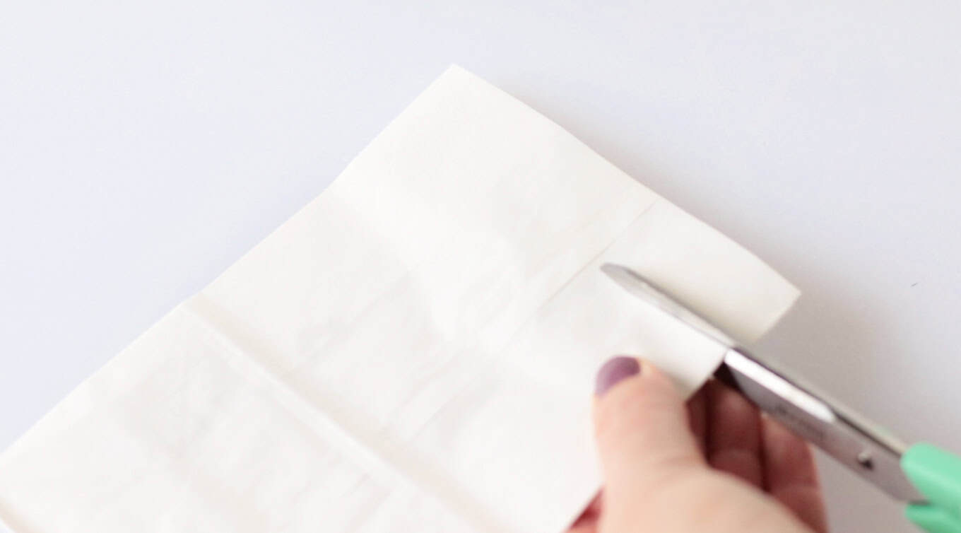 Scissors cutting slits into white bag.