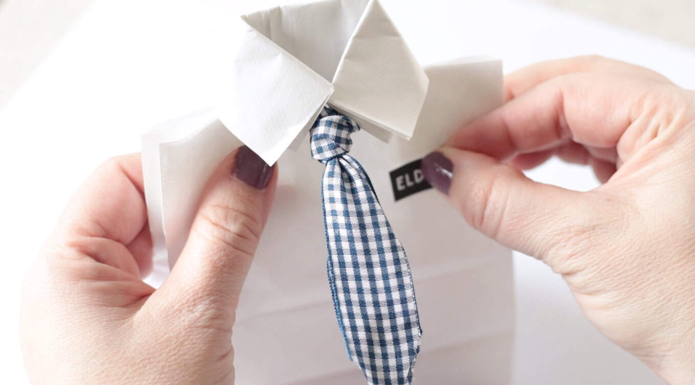 Hands placing missionary name tag on paper bag.