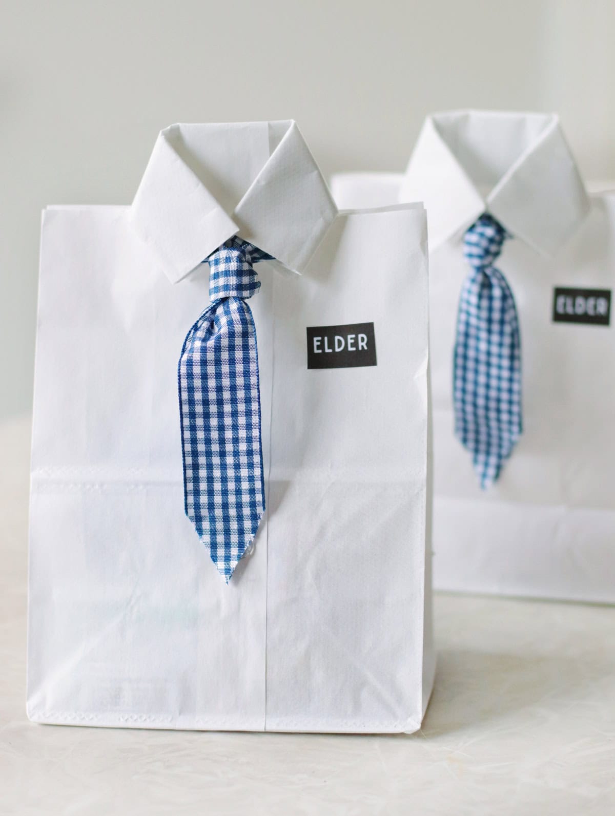 Two paper bags decorated to look like missionary shirts and ties.