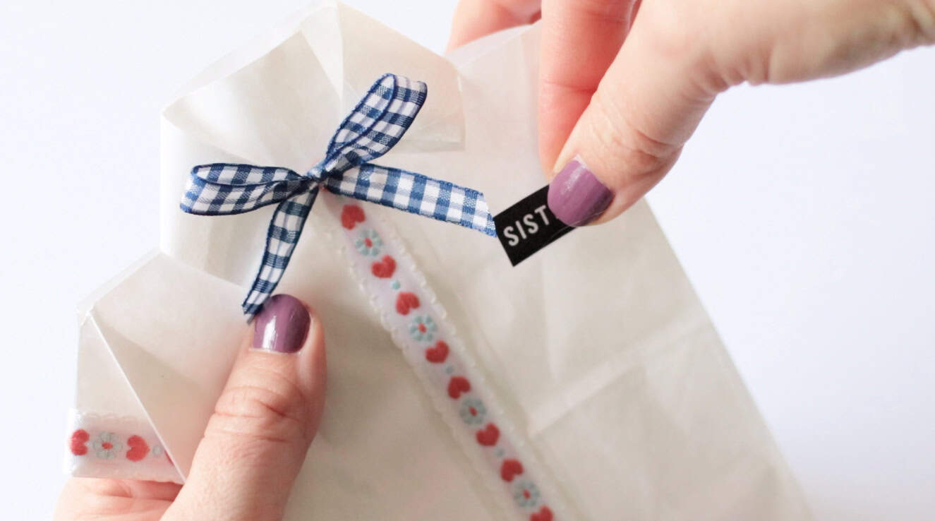 Fingers attaching missionary name tag to paper bag.