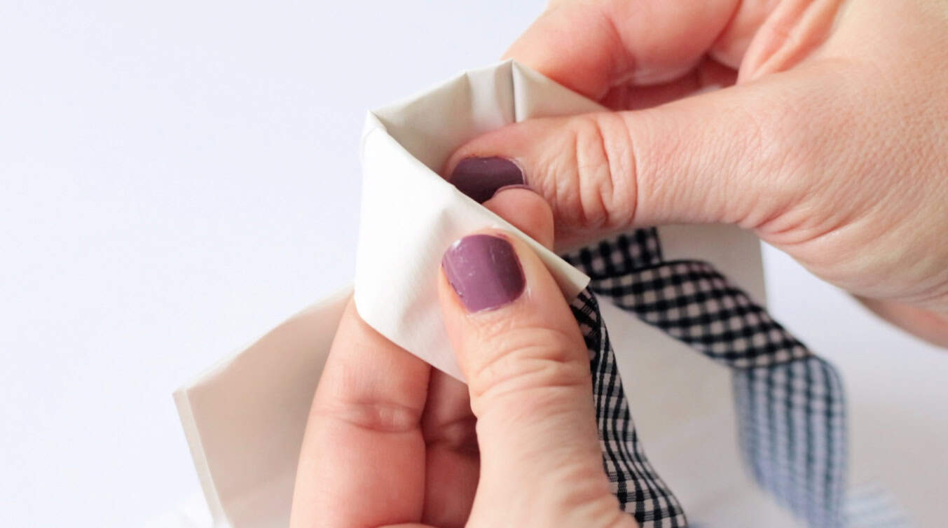 Hands folding a bag to look like a shirt collar.