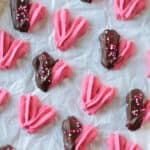 Cookie sheet of heart shaped danish cookies with some dipped in chocolate.