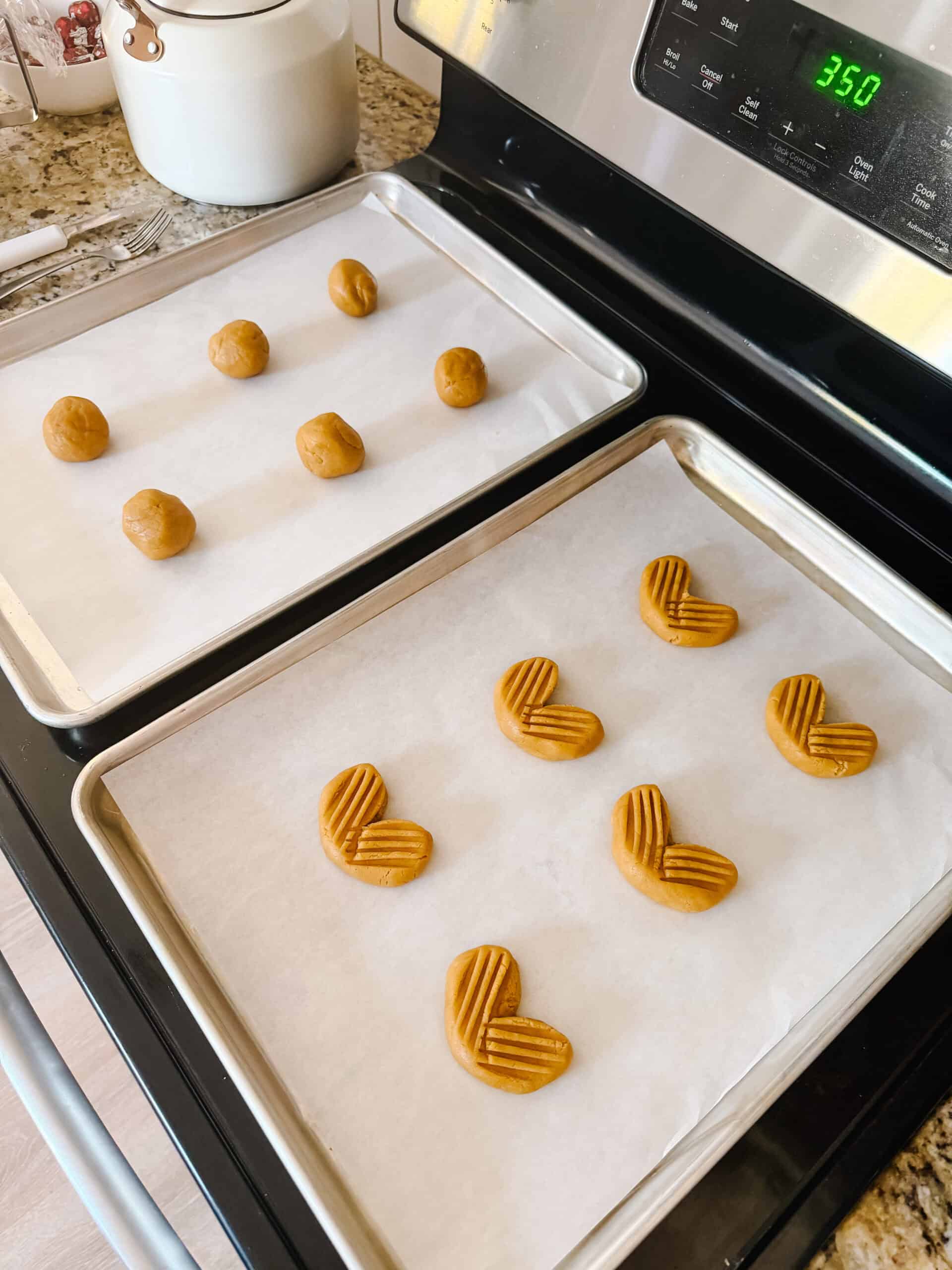 Two baking sheets with cookie dough balls.
