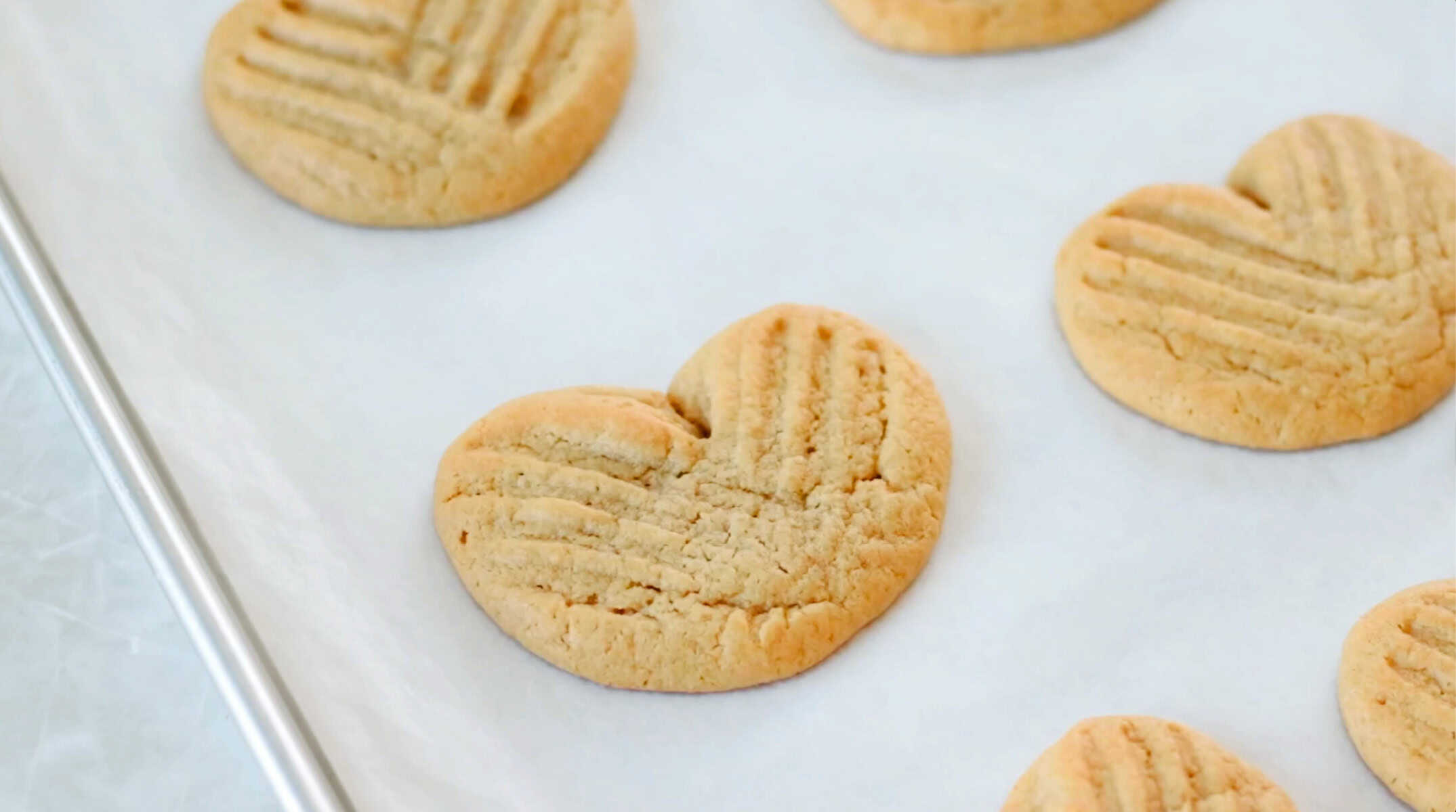 Heart shaped peanut butter cookies on a baking sheet.