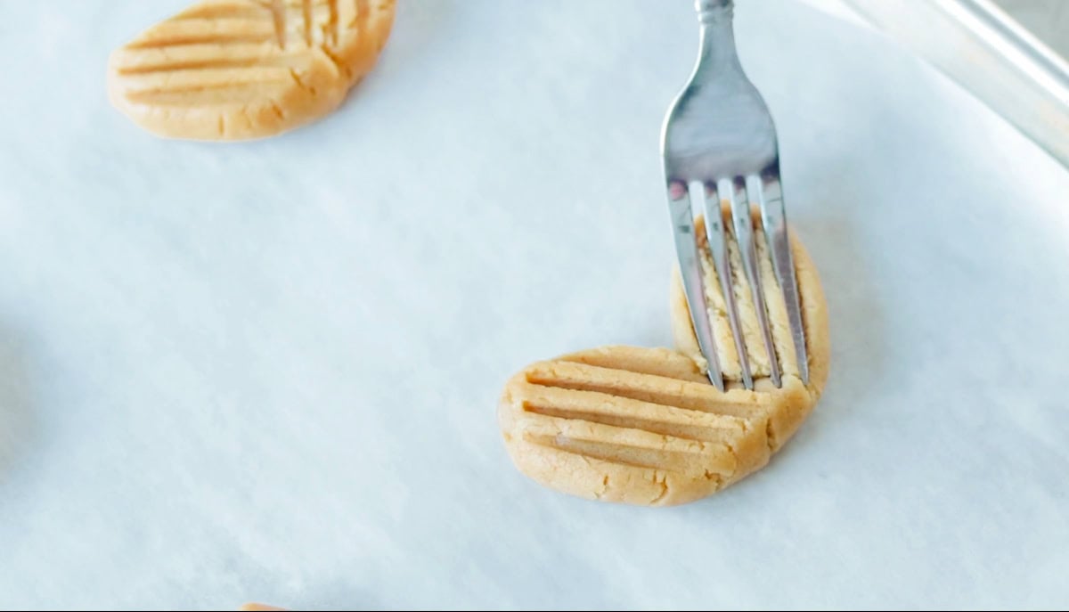 Fork pressed down into each heart shaped cookie dough.