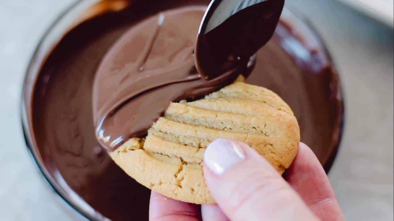 Spoon spreading chocolate over peanut butter cookie.