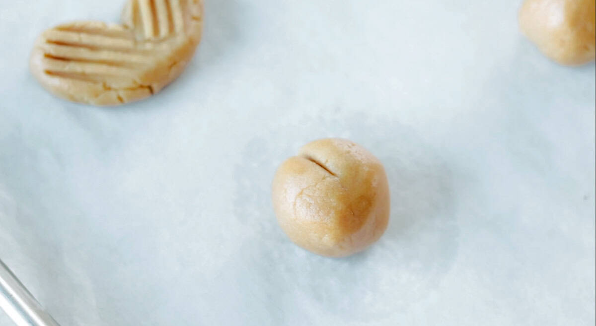 Balls of peanut butter cookie dough with slit in the top.