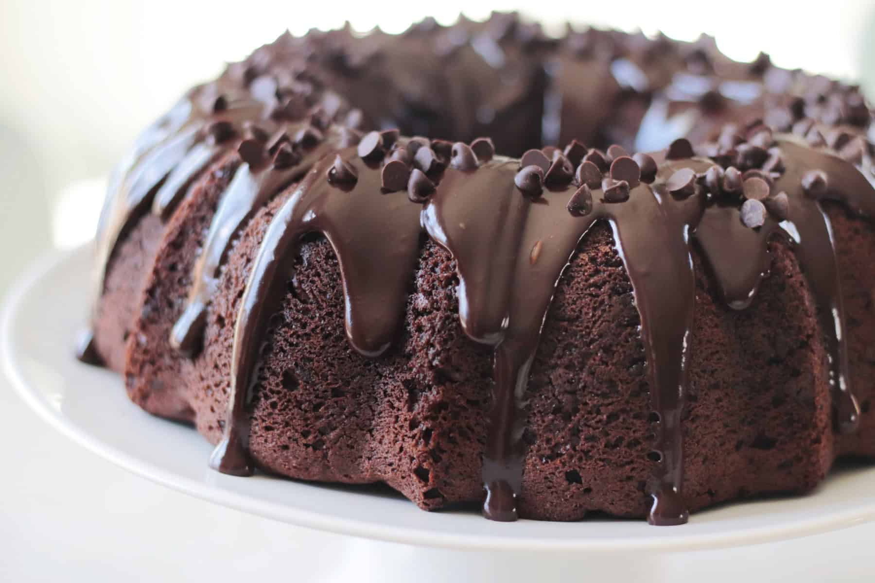 Chocolate pudding bundt cake on white cake stand.