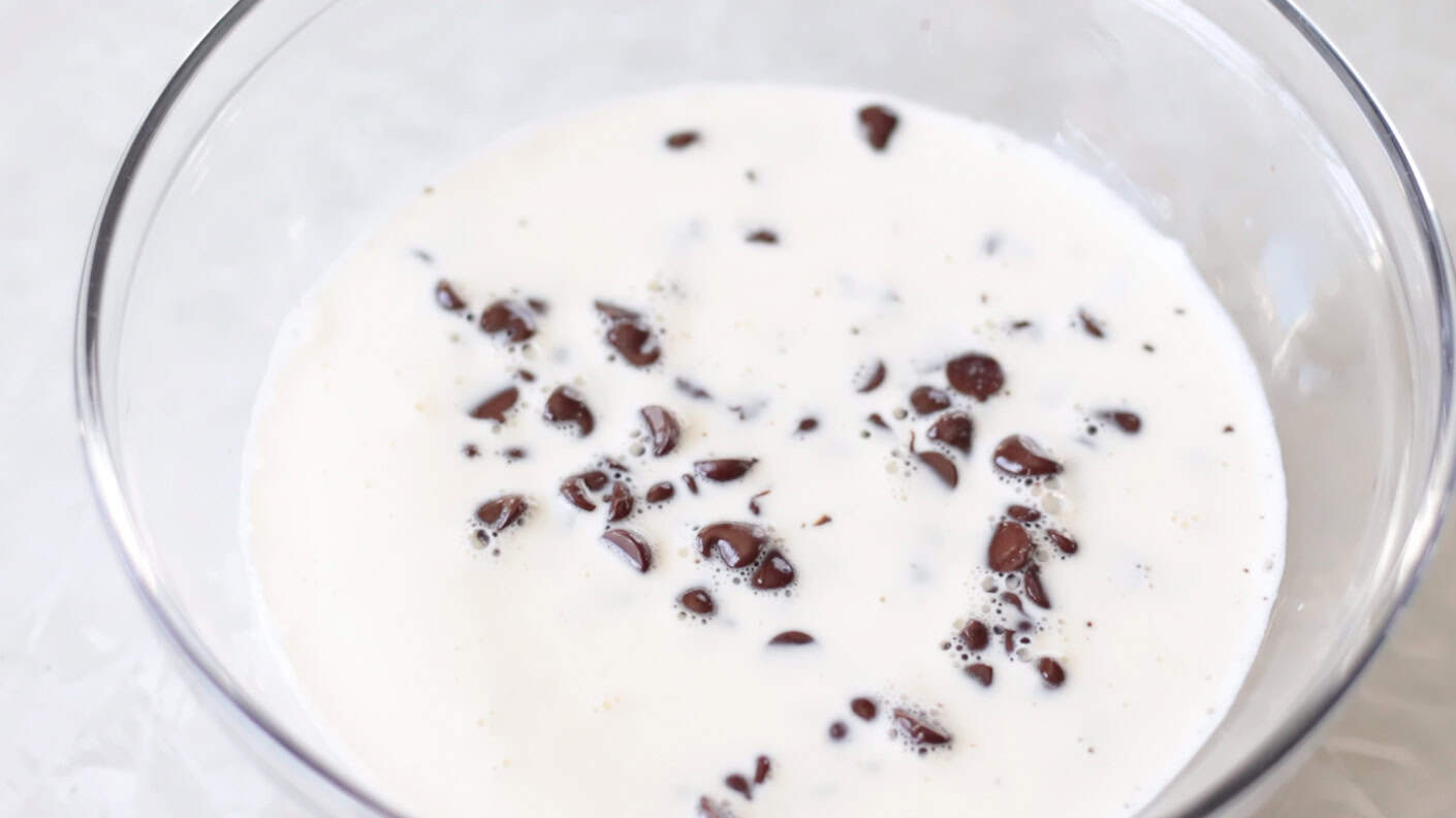 Bowl of hot cream poured over chocolate chips.
