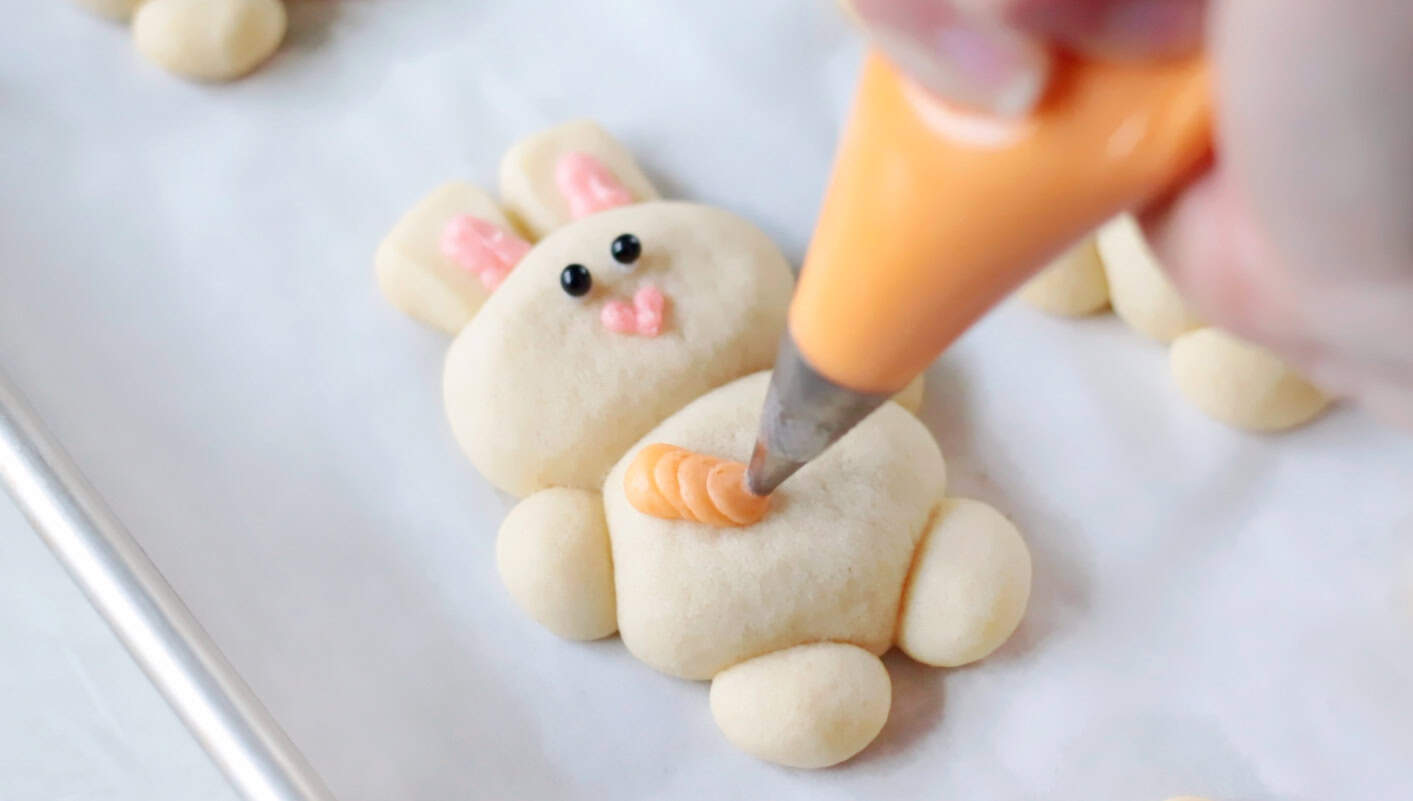 Orange buttercream piped onto cookie in the shape of a carrot.