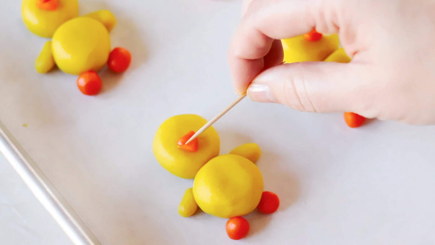 Toothpick pressing line on sugar cookie chick beak.