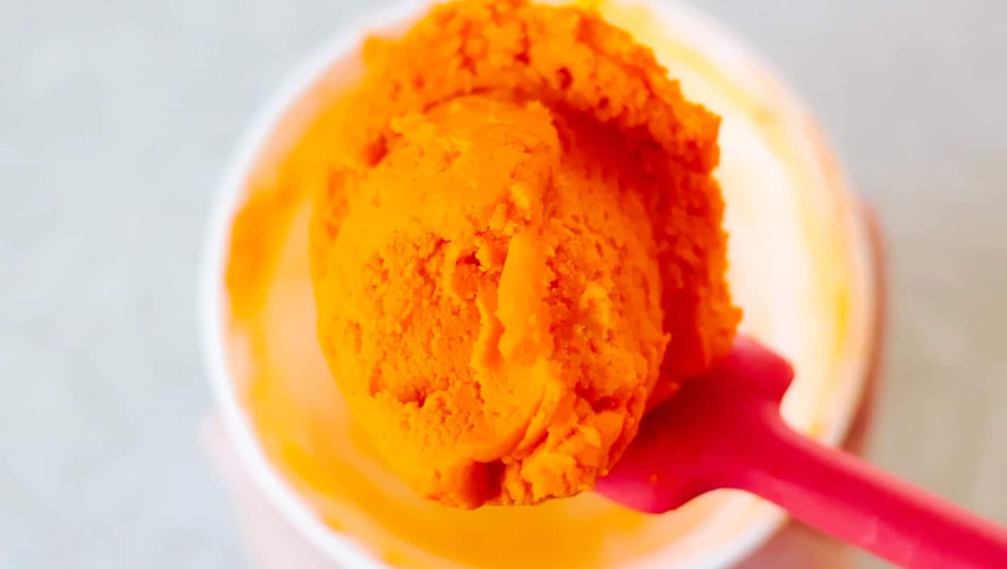 Orange sugar cookie dough on a spatula.