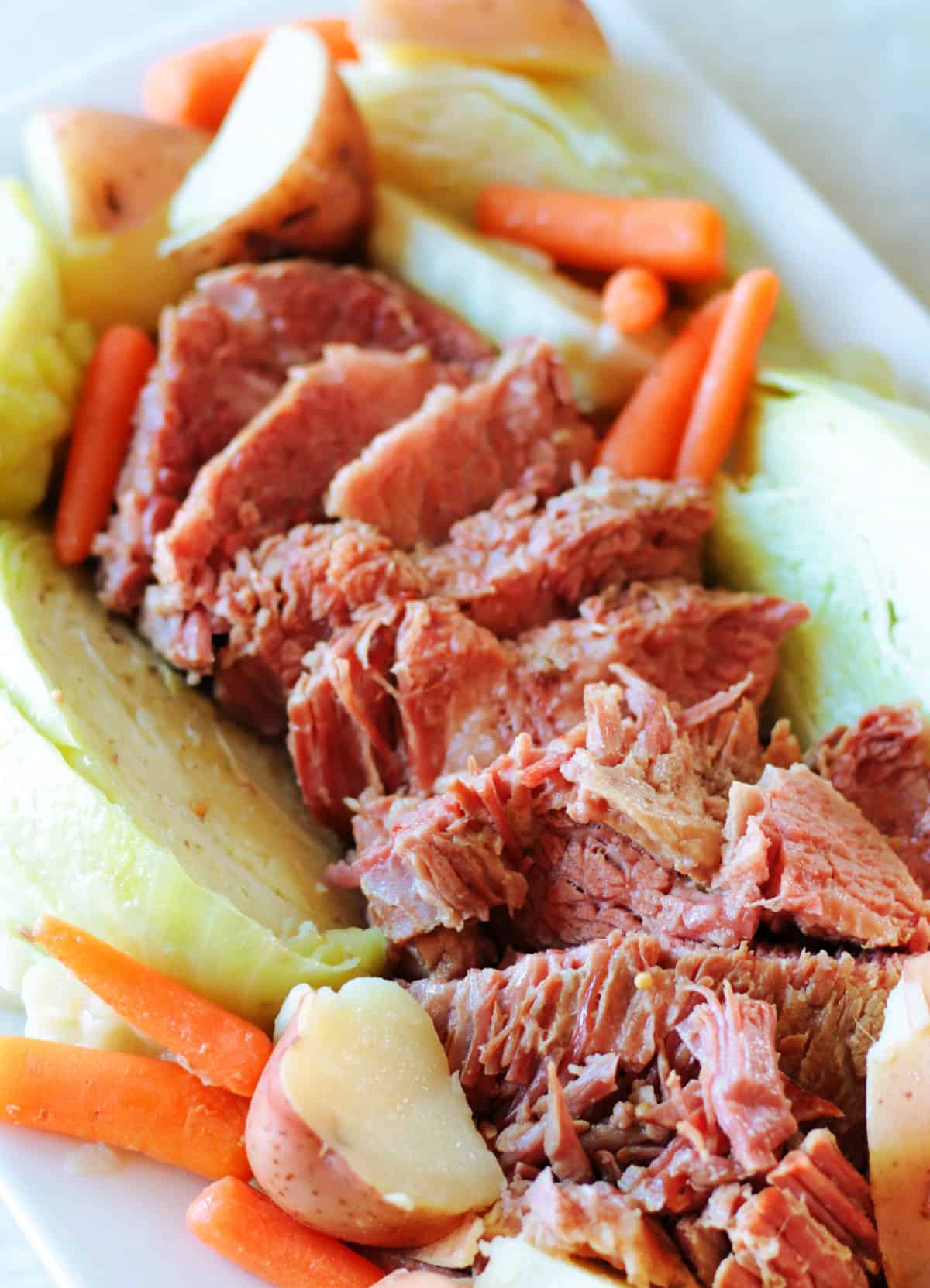 Corned beef, cabbage, carrots, potatoes and roll in serving dish.
