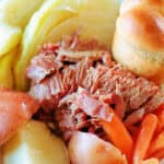 Corned beef, cabbage, carrots, potatoes and roll in serving dish.