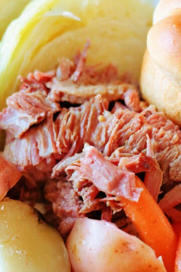 Corned beef, cabbage, carrots, potatoes and roll in serving dish.