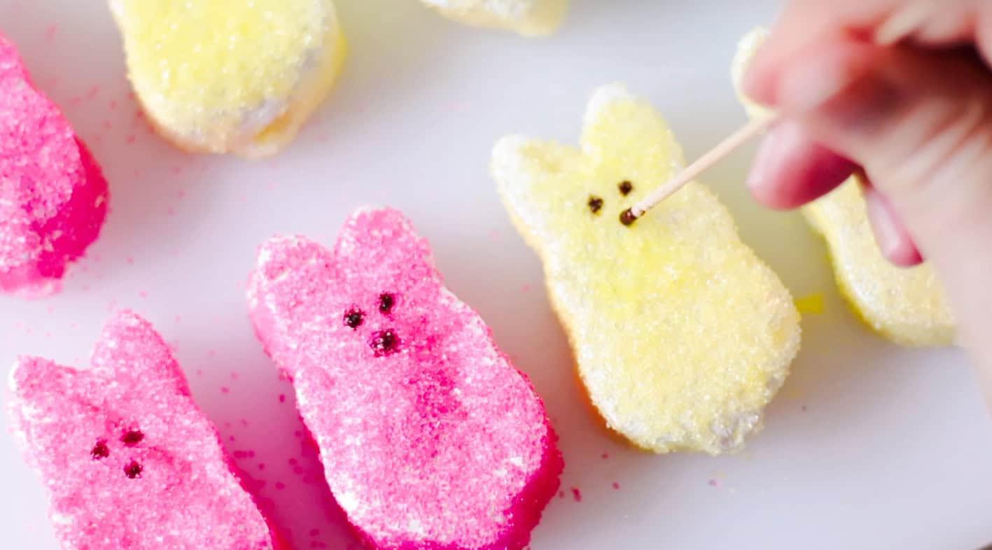 Toothpick dabbing bunny marshmallows with cocoa water for eyes.