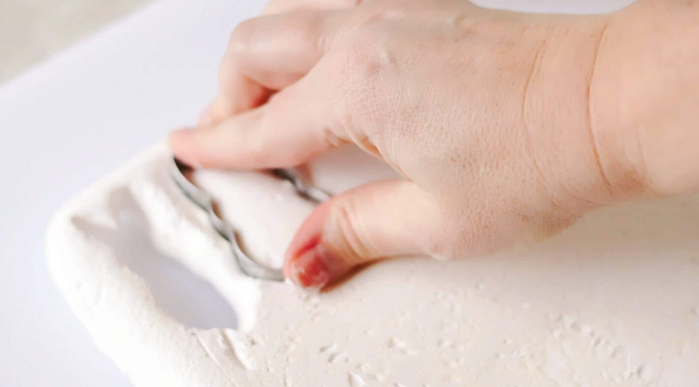 Hand cutting out bunny shape marshmallow using cookie cutter.