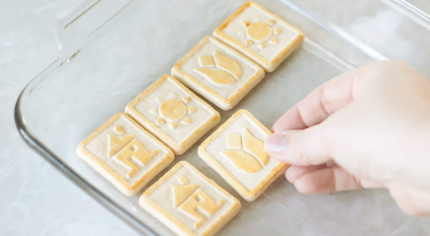 Hand placing butter cookies in bottom of baking dish.