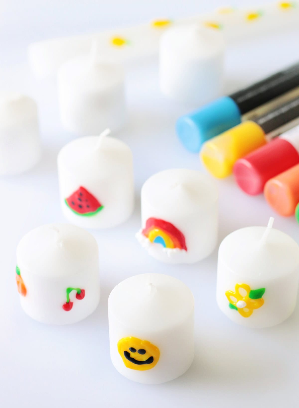Variety of candles decorated with colorful wax pens.