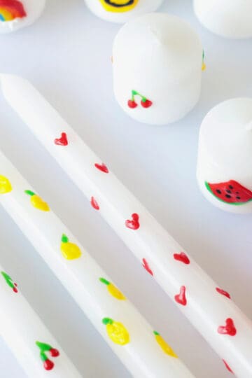 White candles decorated with wax candle pens.