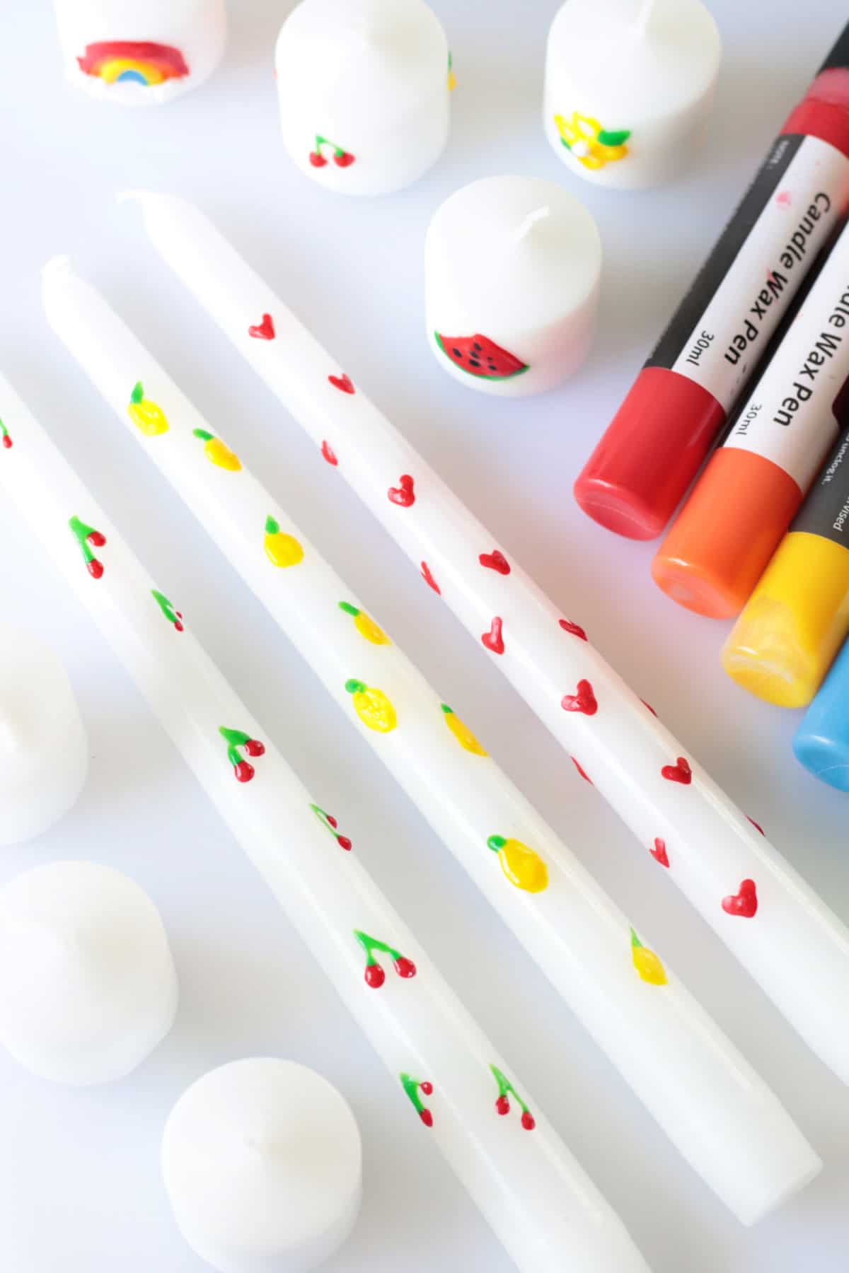 White taper and votive candles decorated with wax pens.
