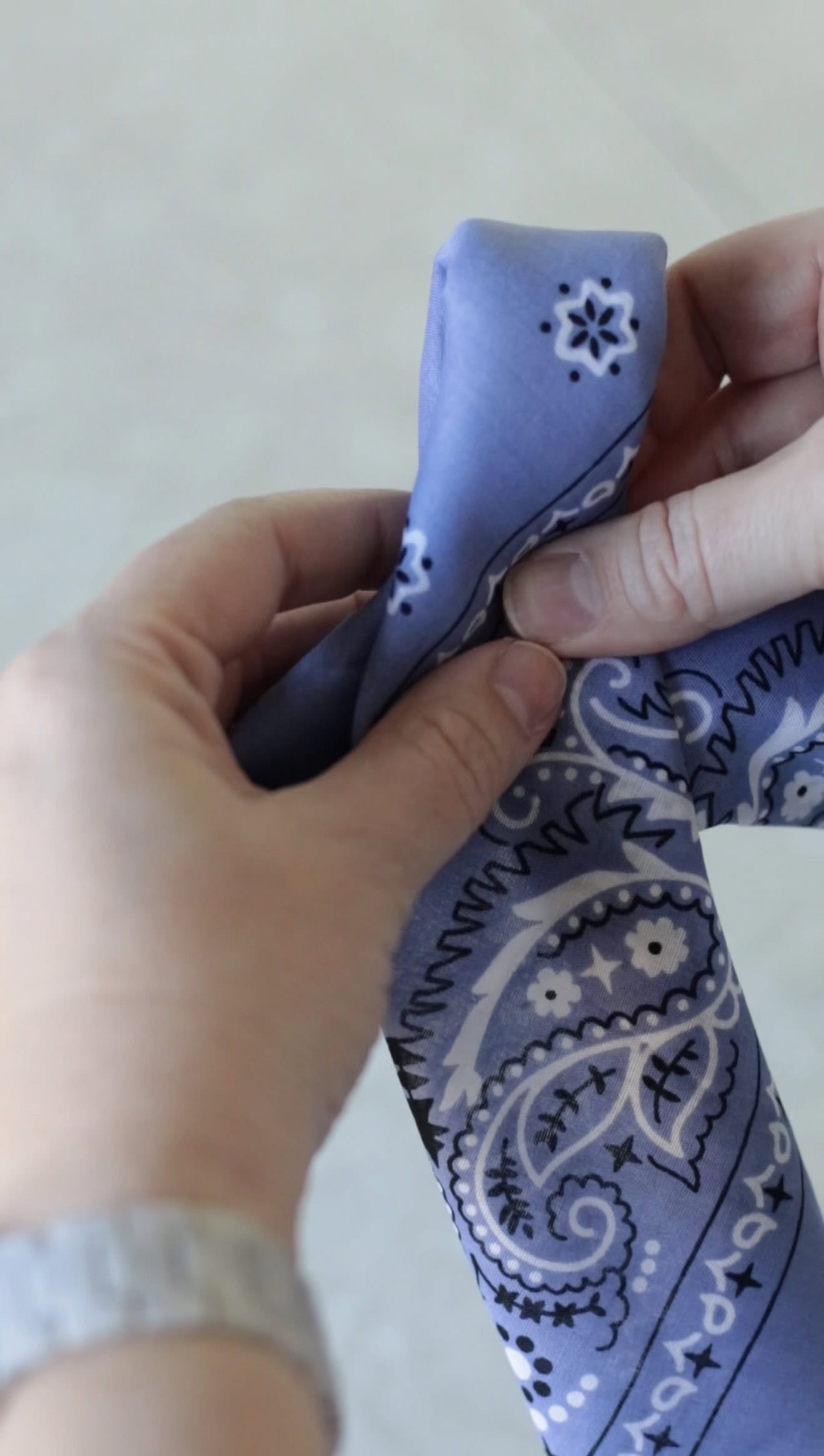 Hand pinching bandana into hair bow shape.