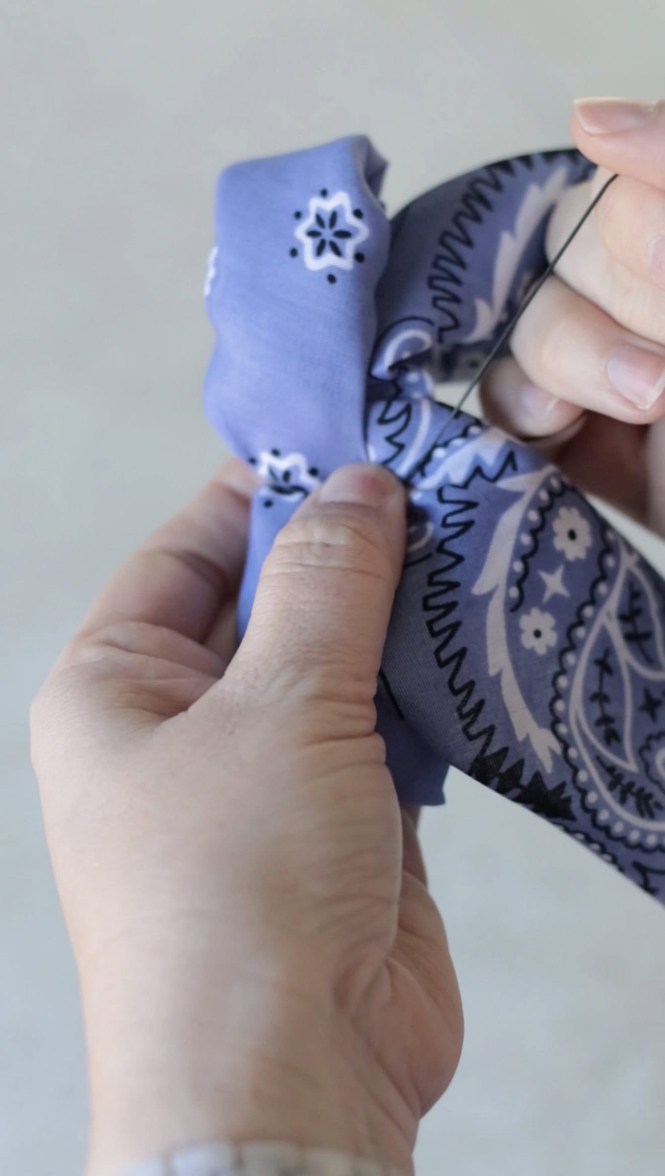 Hand tying rubber band around bandana.