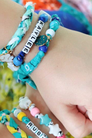 Arms with stacks of bandana bracelets on them.