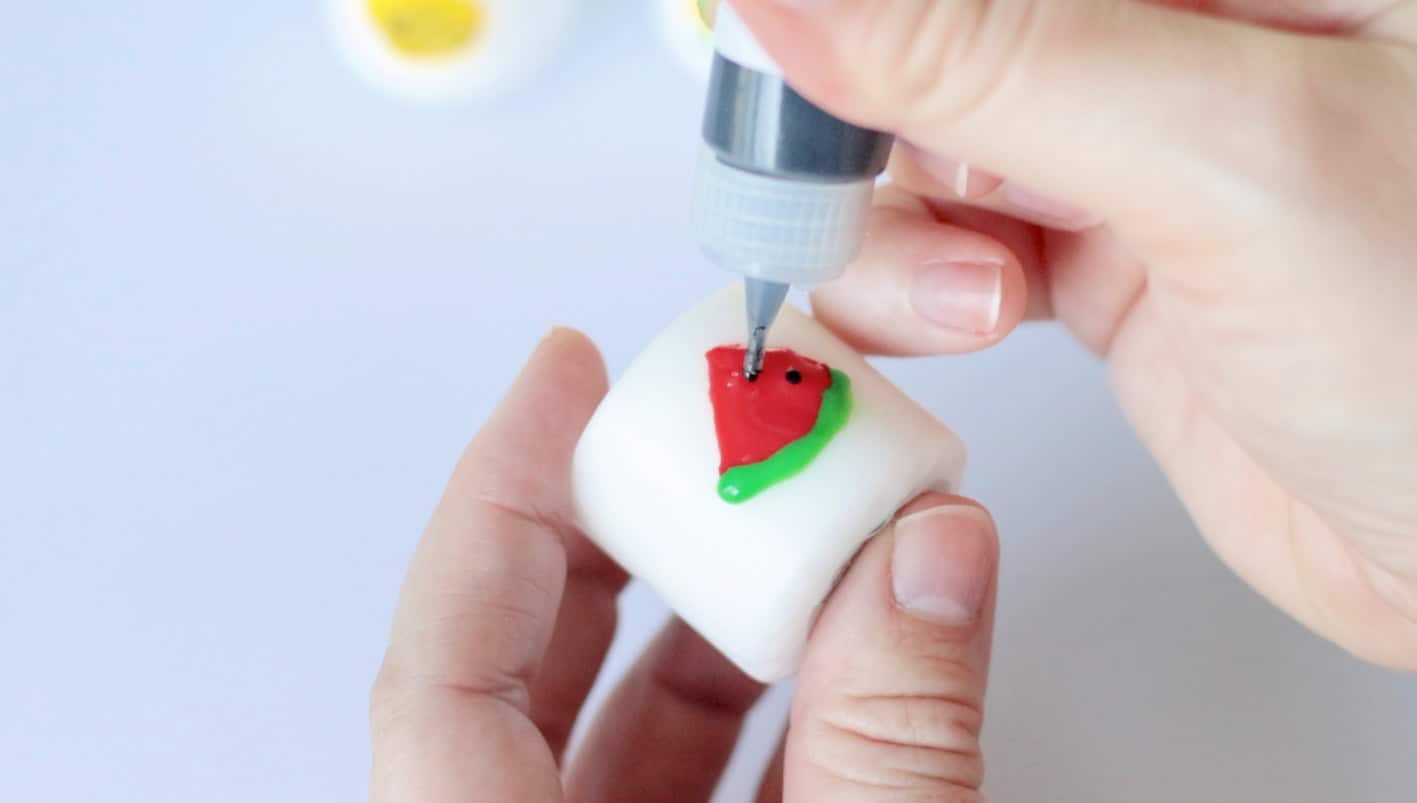 Wax candle pen decorating a white votive candle.