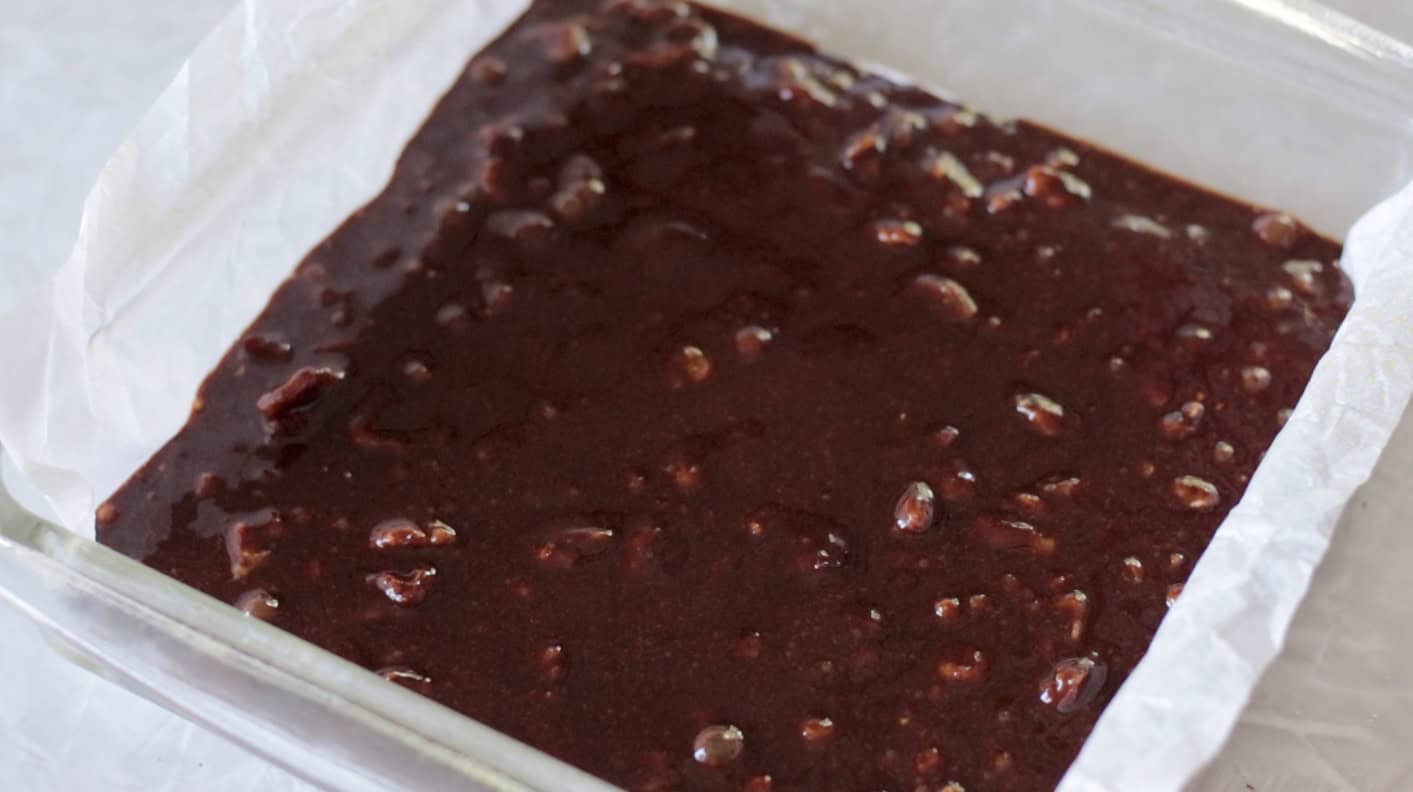 Brownie batter poured into prepared baking dish.