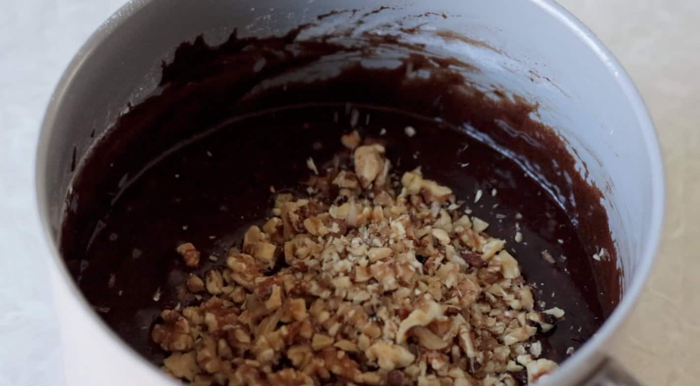 Chopped walnuts in pan with brownie batter.