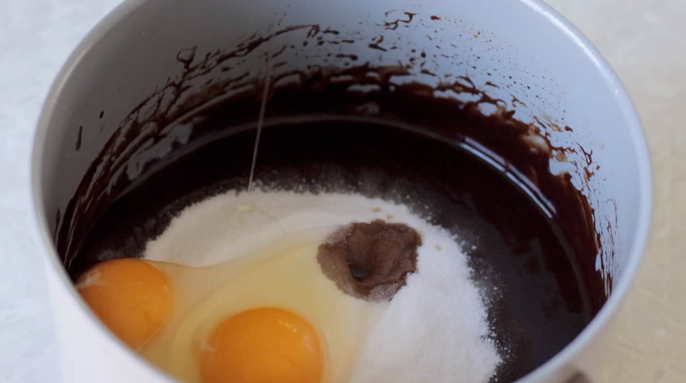 Eggs and sugar in saucepan with butter and chocolate mixture.