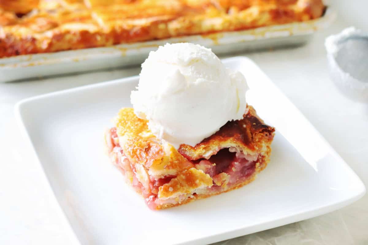Slice of slab pie on a plate with vanilla ice cream.