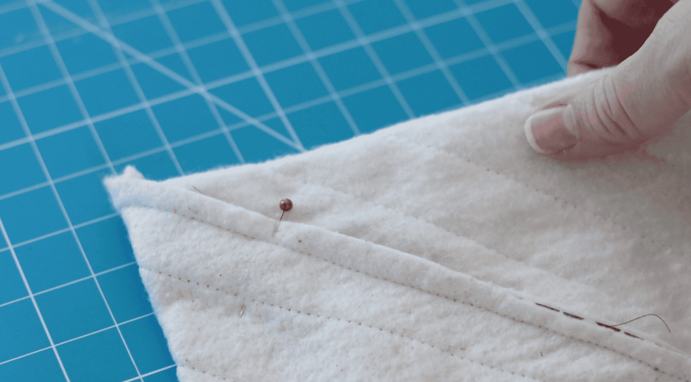 Quilted fabric with batting pressed flat and pinned in the corner.