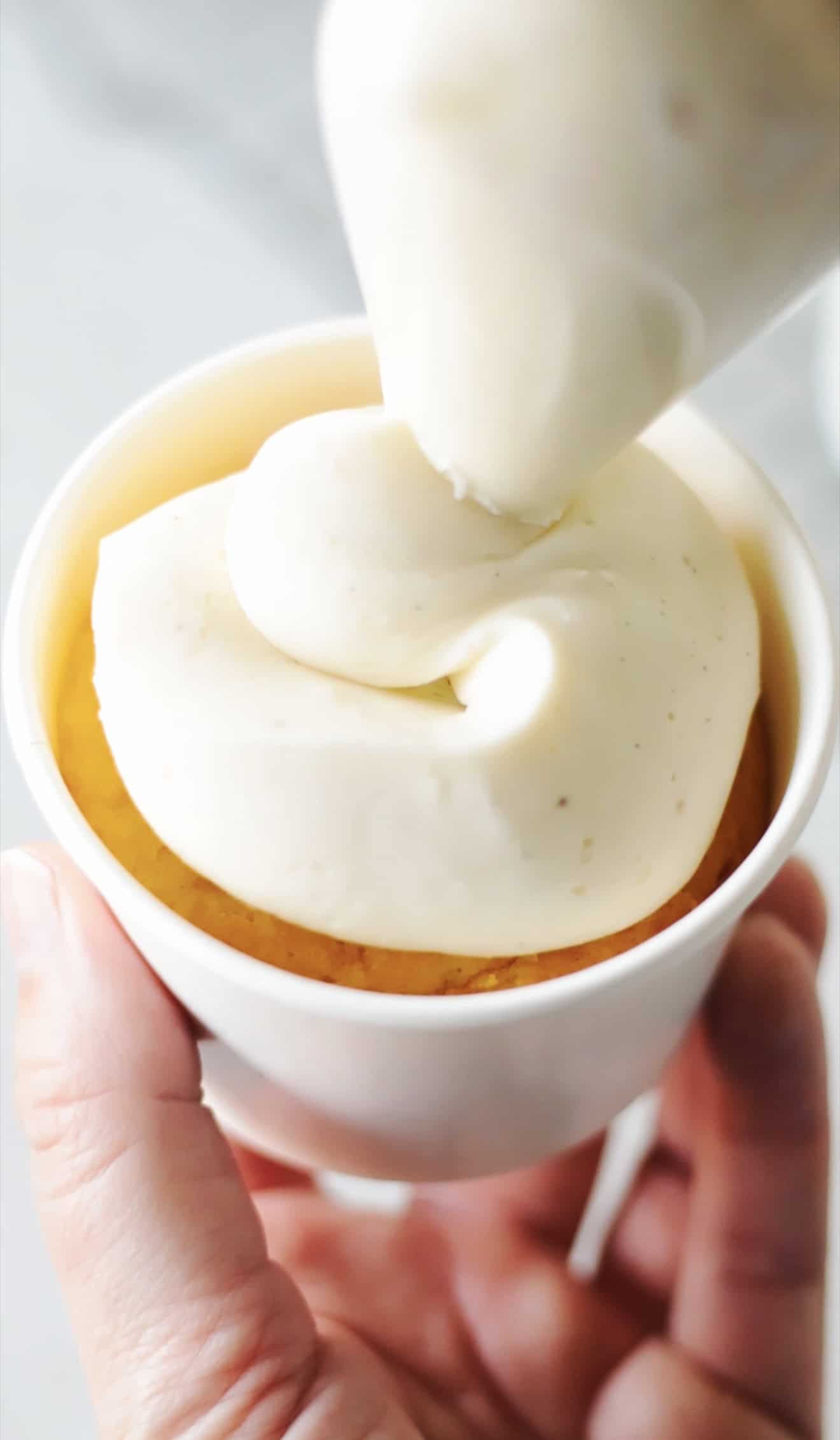 Buttercream piped over cupcake in cup.