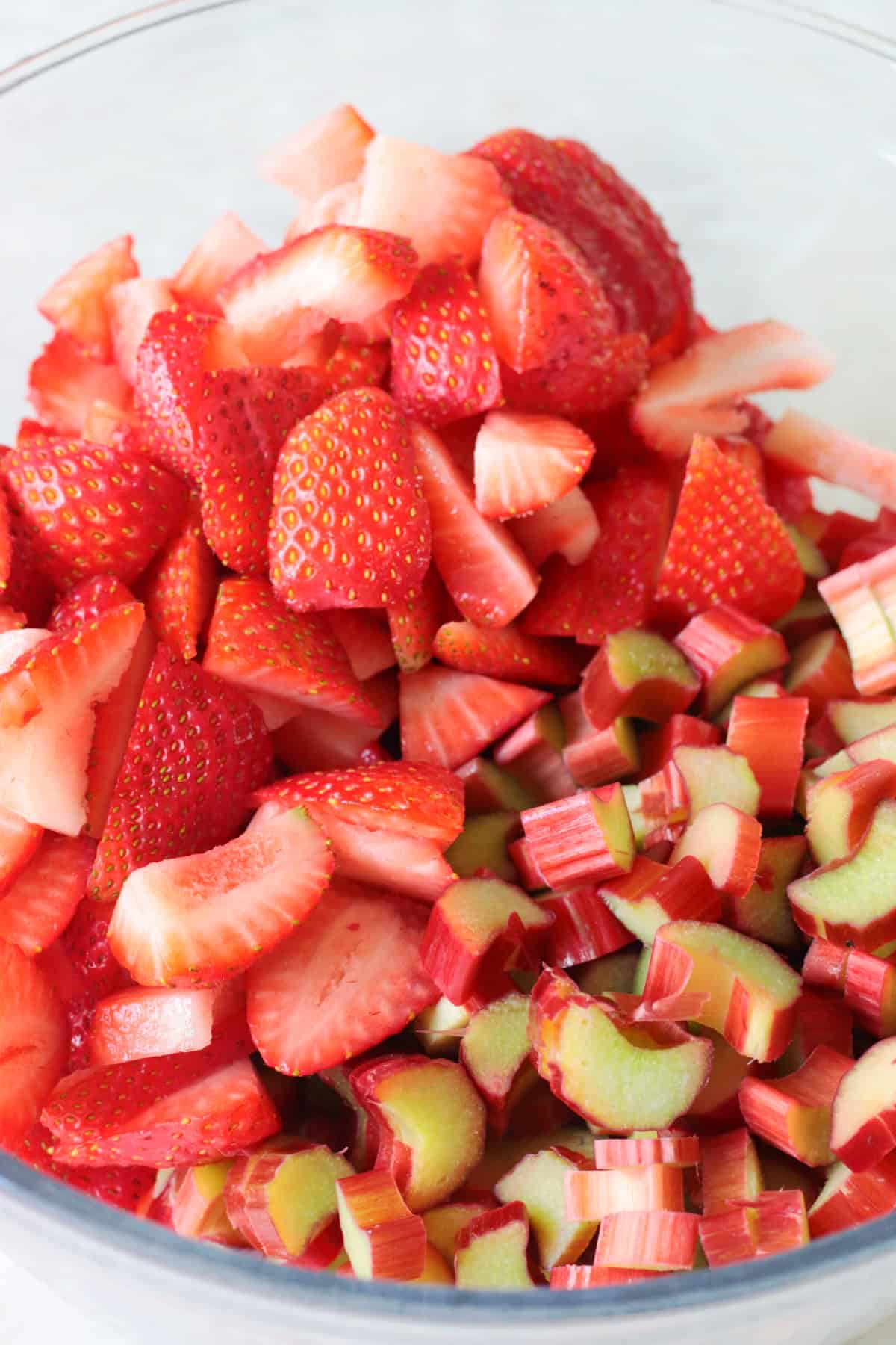 Sliced strawberries and sliced rhubarb in a glass bowl.