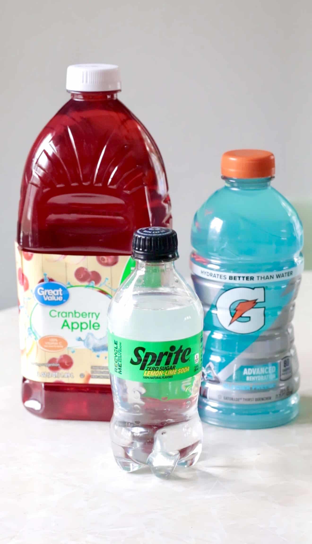 Bottles of cran apple juice, blue gatorade and sprite.