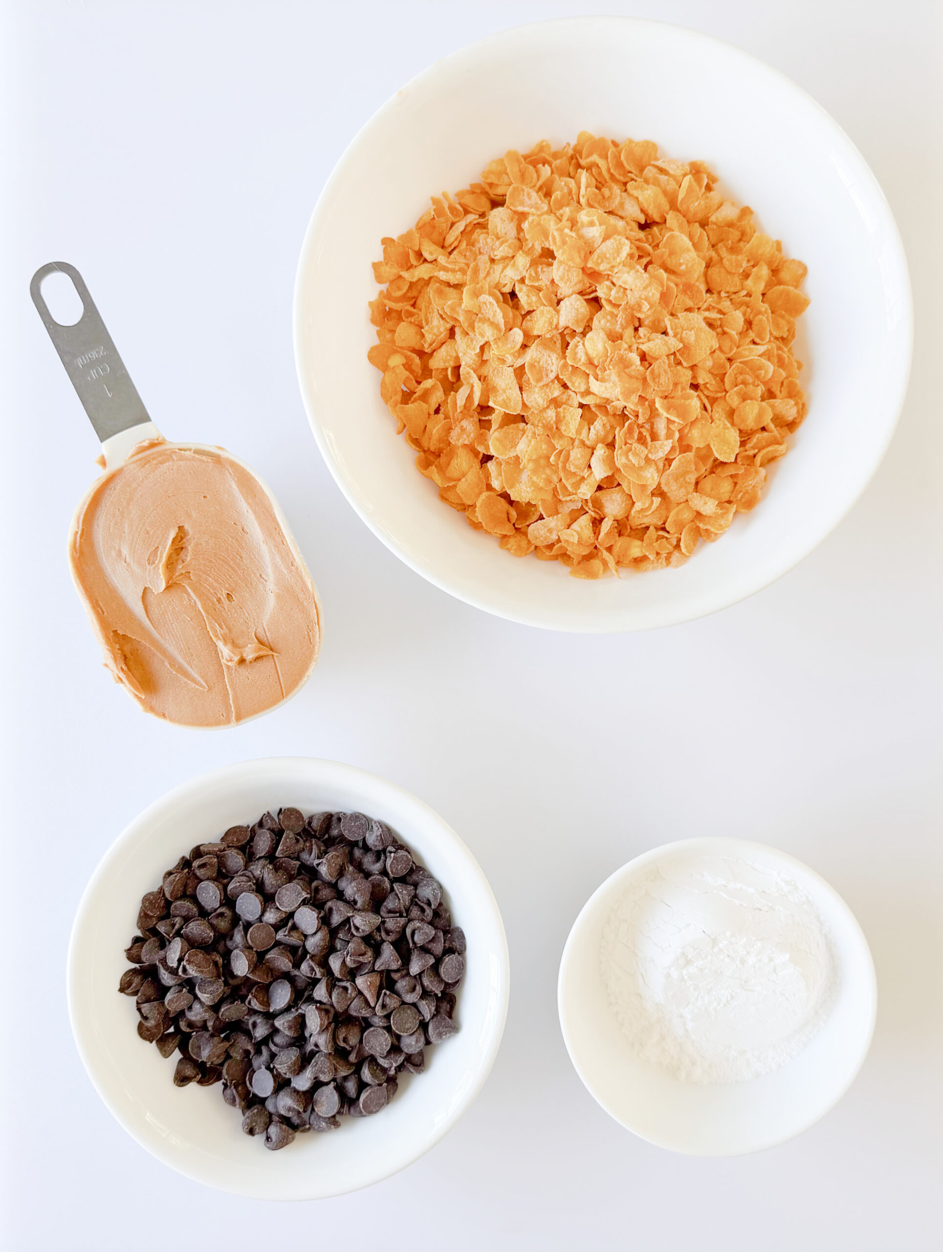Bowls of chocolate chips, corn flakes, peanut butter and powdered sugar.