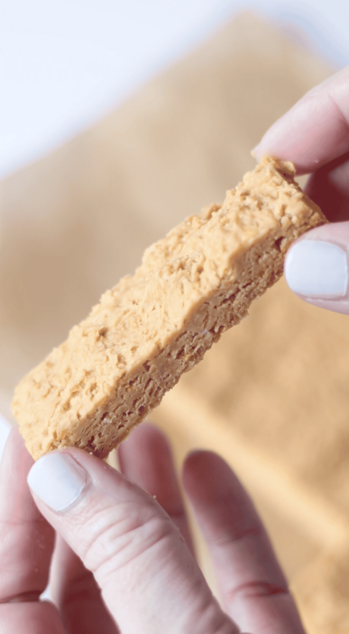 Hand holding butterfinger not dipped in chocolate.
