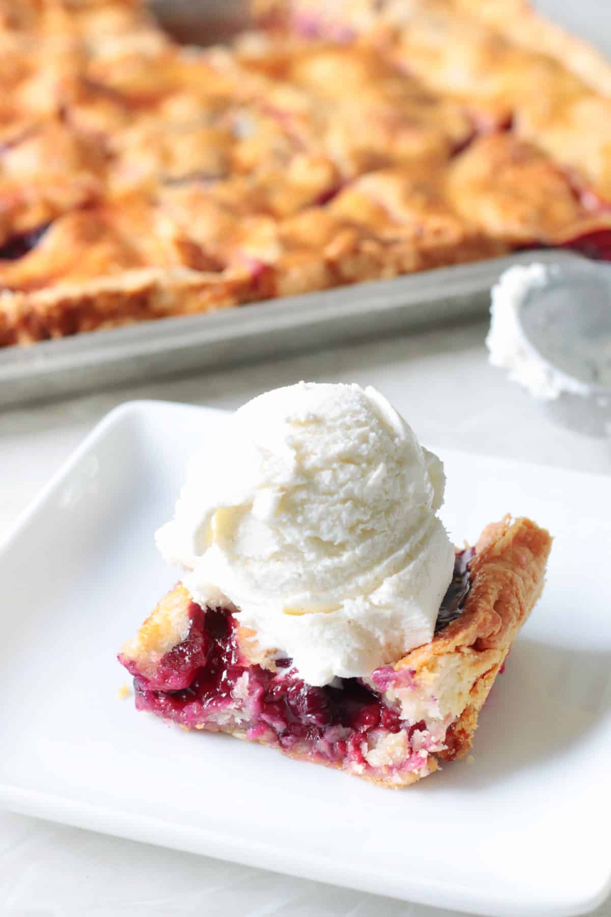Slice of pie on white plate with ice cream.