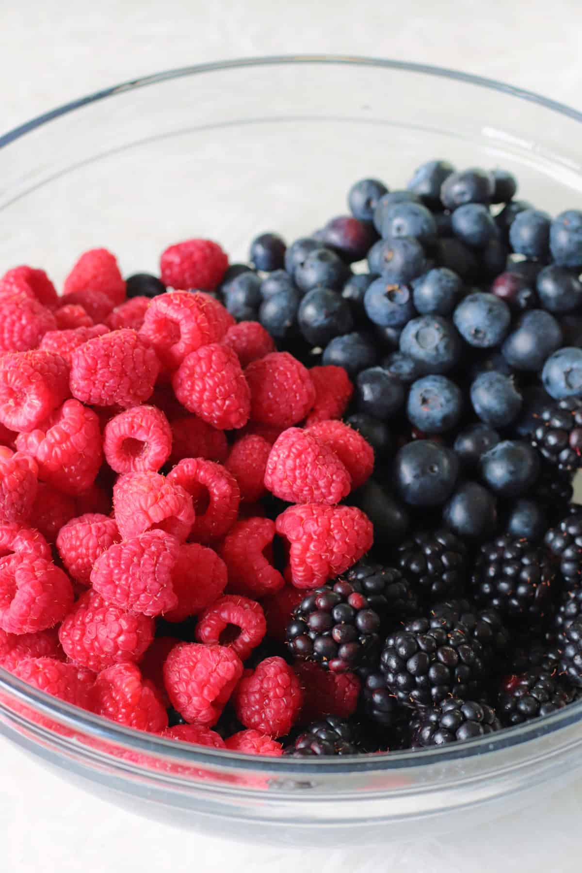 Glass bowl of blackberries, blueberries and raspberries.