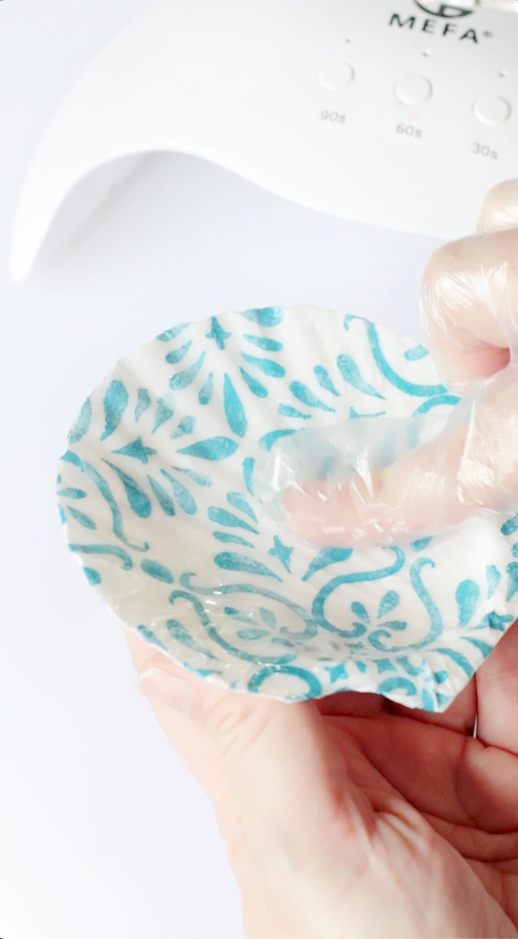 Gloved hand spreading resin across the shell.
