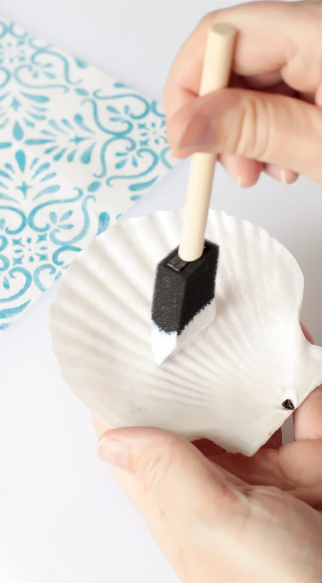 Sponge brush applying Mod Podge onto plain scallop shell.