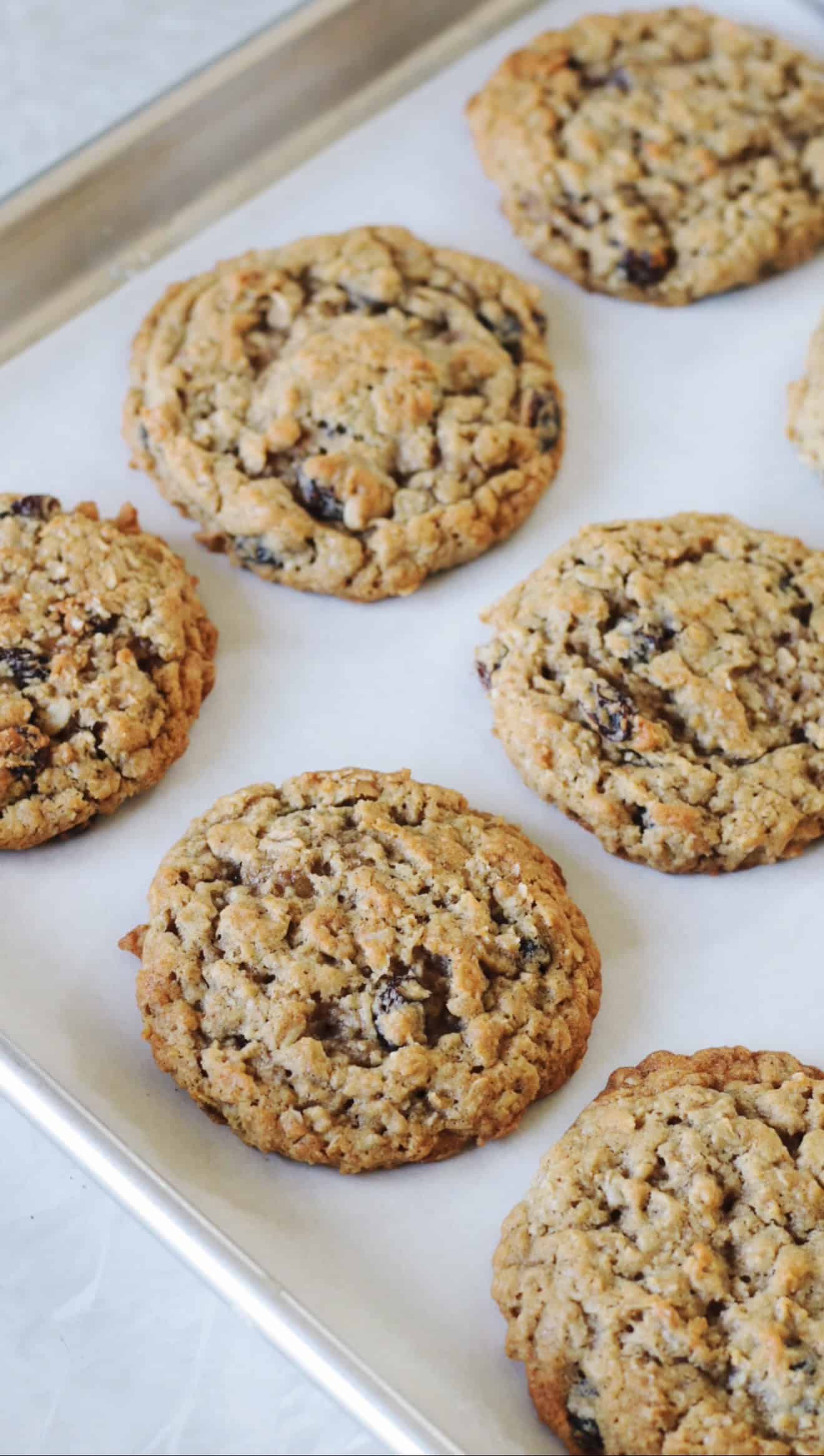 Oatmeal raisin cookies on a parchment lined baking sheet.