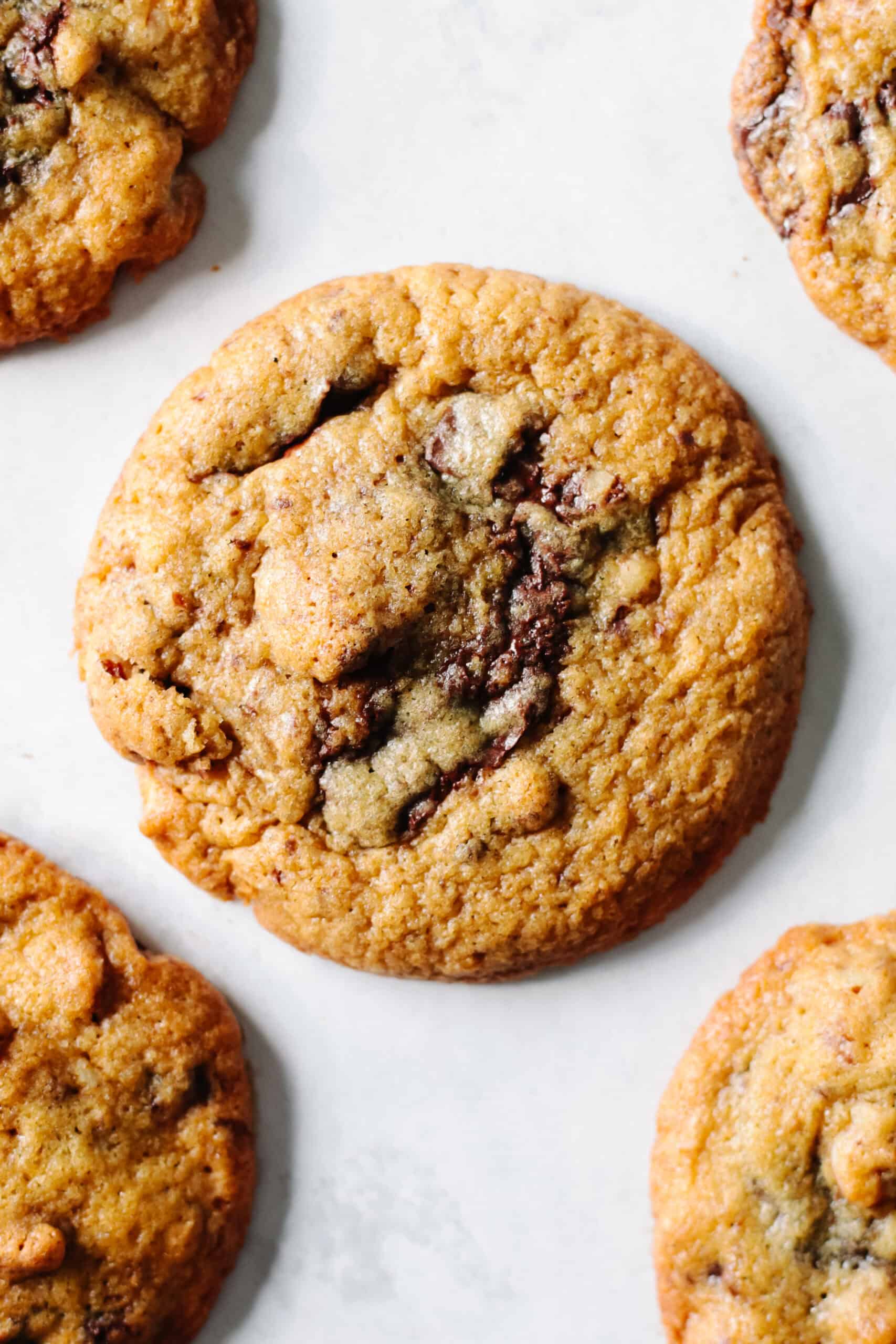 Chocolate chunk pecan cookies on a piece of parchment paper.
