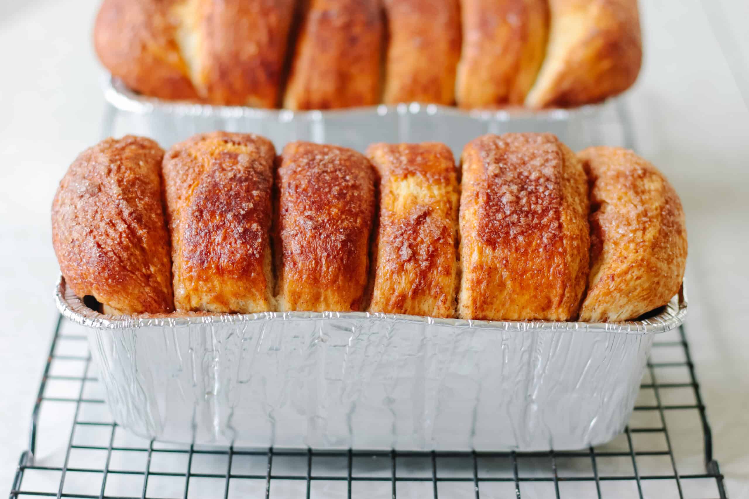 Two loaves of cinnamon bread in pans.