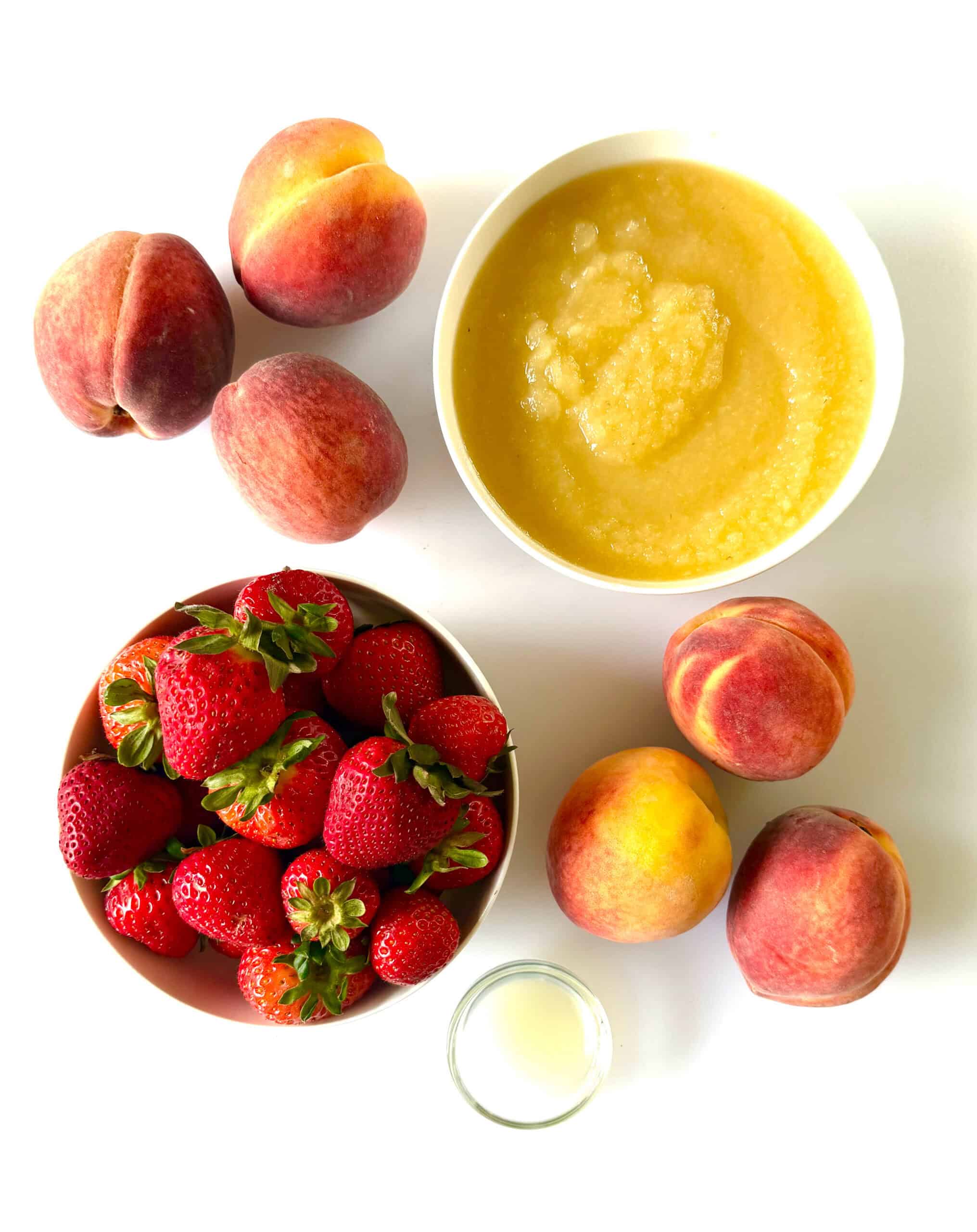 Bowls of strawberries, applesauce, lemon juice, and fresh peaches.