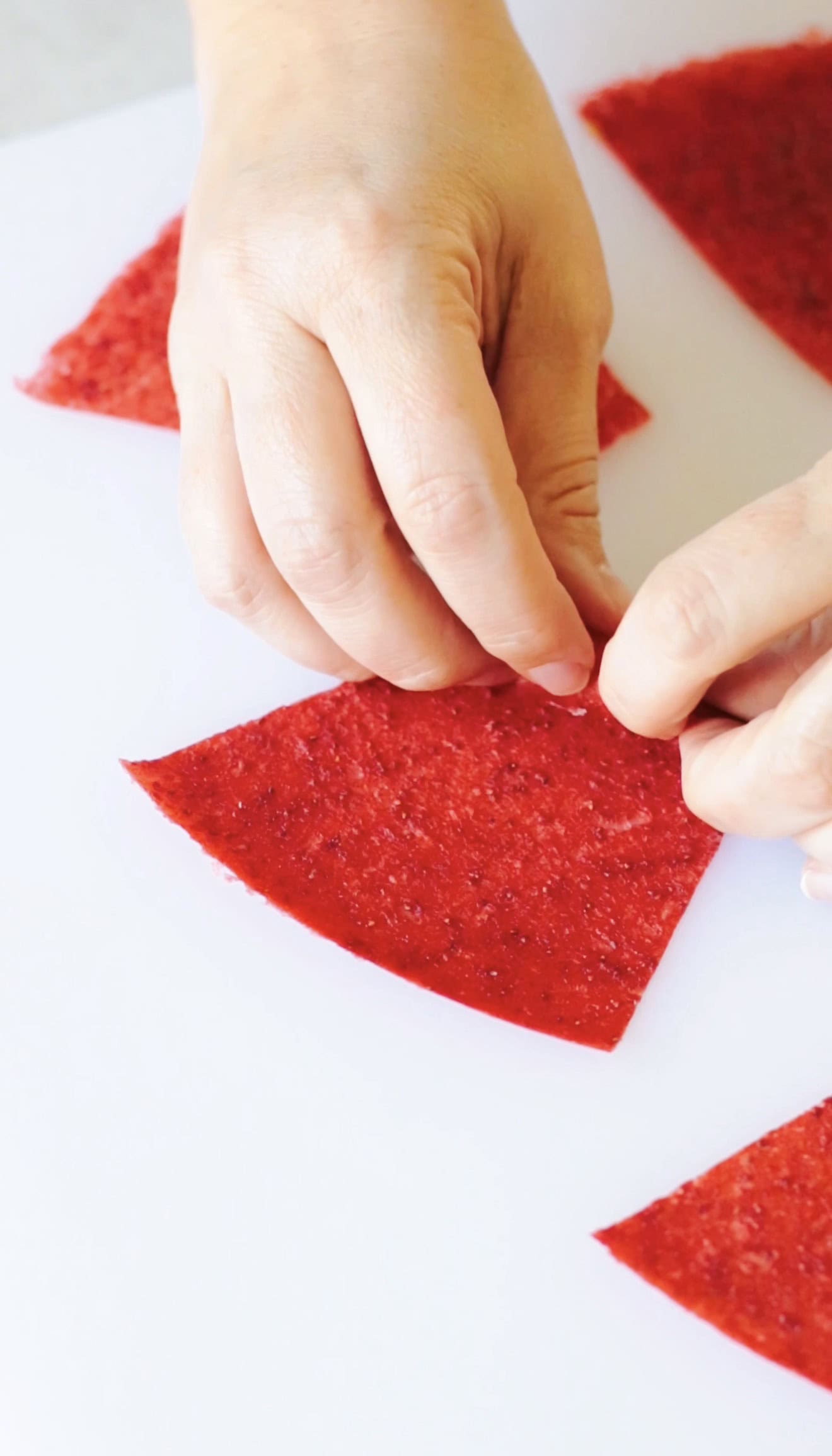 Hand rolling up strawberry fruit leather.